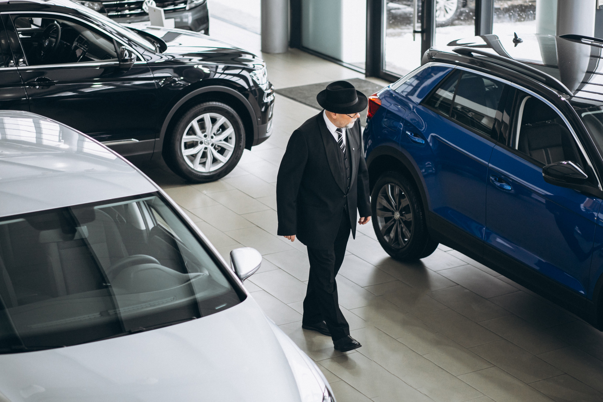 A man browsing multiple cars in a modern Dubai car showroom in BV Car Dubai