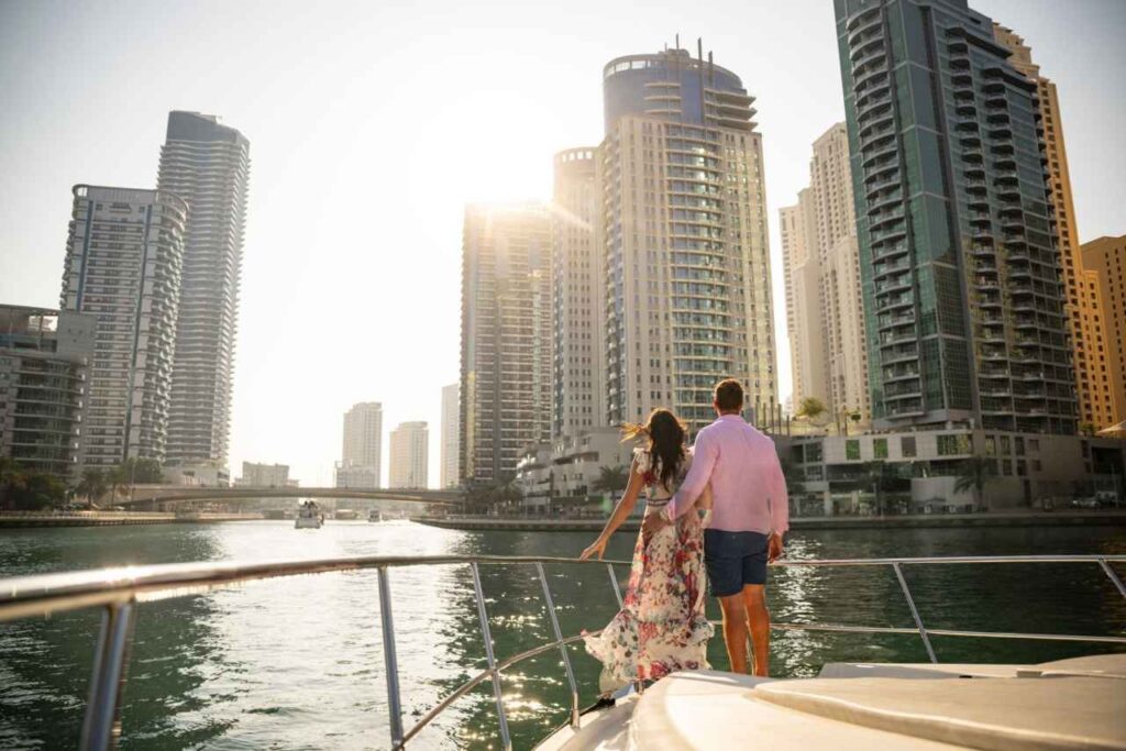 A couple enjoying yacht tour in dubai marina in front of high buildings| marsa al arab