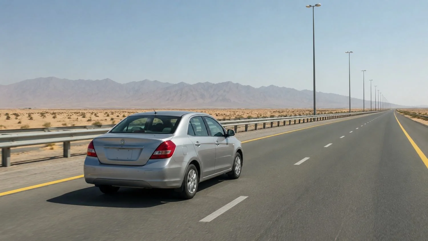 Rental car driving on the E66 highway between Dubai and Al Ain with desert scenery